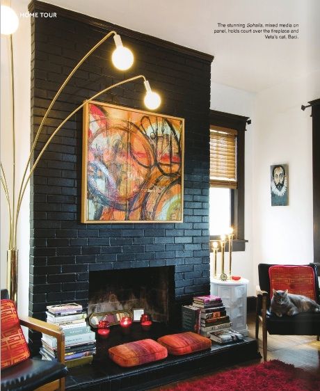 painted black fireplace, vintage light, teak chairs, stacks of books